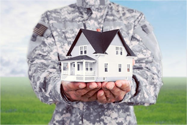 Servicemember in uniform holding house in hands