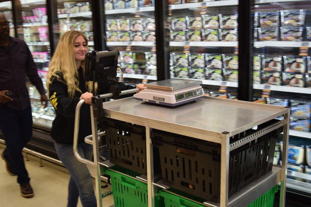Madison Zundel, a CLICK2GO picker, moves through the Fort Eustis Commissary, Virginia, with the item collection cart. (DeCA/Richard Brink)