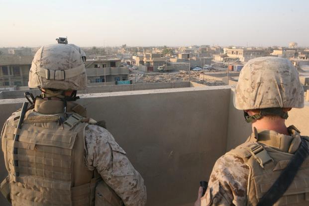Petty Officer 3rd Class Benjamin Swain, front, a corpsman with 3rd Battalion, 11th Marine Regiment, Regimental Combat Team 1, and Maj. Jeffrey McCormack, the operations officer for 1st Battalion, 9th Marines, glance over the city of Fallujah from the roof a building, Sept. 17, 2008. The roof of the building was the last place McCormack saw James, Benjamin's brother, alive. (Casey Jones/U.S. Marine Corps)