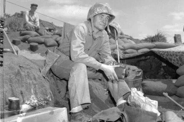 Marine Sgt. Arthur J. Kiely Jr. sits on in a position on Pacific island during World War II, wearing the 1911 Colt .45 automatic pistol.
