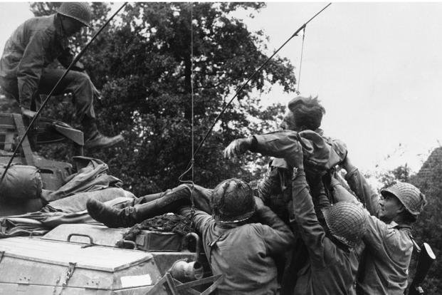 American soldiers lift a wounded German prisoner into an armored car during World War II.