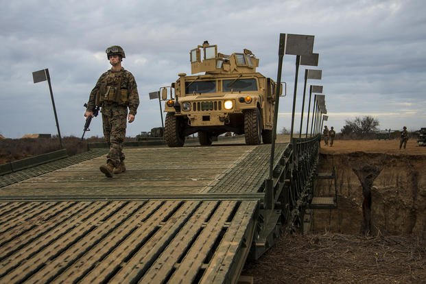 Marine Corps Cpl. Matthew Morrow guides a High Mobility Multipurpose Wheeled Vehicle across a bridge constructed at Marine Corps Base Camp Pendleton, California.