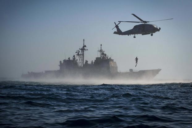 The guided-missile cruiser USS Monterey and an MH-60R Sea Hawk helicopter assigned to Helicopter Maritime Strike Squadron Forty-Eight conduct search and rescue training evolution on Sept. 23, 2016. Petty Officer 2nd Class William Jenkins/Navy