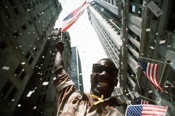 Army Pfc. White waves an American flag while the confetti and tickertape fall on the Welcome Home parade honoring the coalition forces of Desert Storm in New York, June 10, 1991. U.S. Air Force photo by Staff Sgt. Chuck Reger