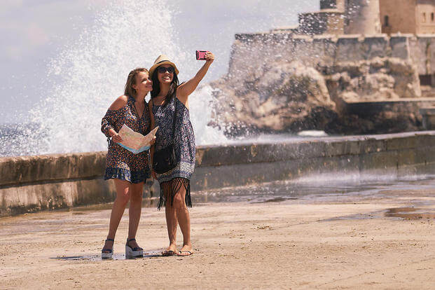 two women taking selfie by a beach