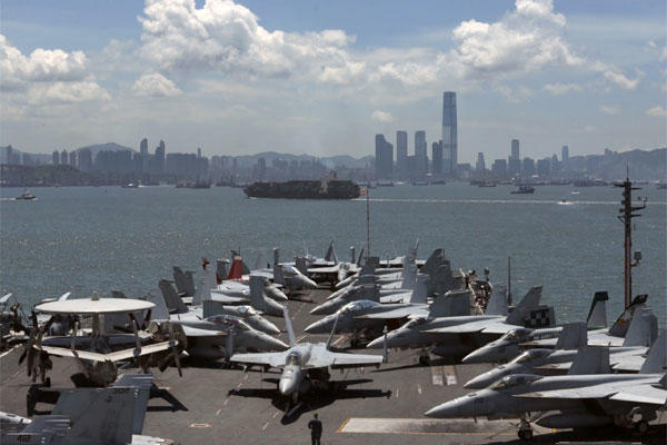 A U.S. Marine patrols beside the F/A-18 fighter jets on the deck of the aircraft carrier USS George Washington in the Hong Kong water for a port call Tuesday, July 10, 2012. (AP Photo/Kin Cheung)