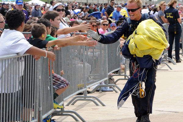 Special Warfare Operator 2nd Class T.J. Amdahl, a member of the Navy Parachute Team, the Leap Frogs, is greeted by the crowd following a demonstration jump at the Air Power Expo air show at Naval Air Station Fort Worth.