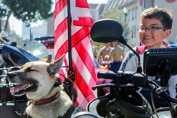 A young boy sits on a motorcycle with a dog while waiting for the Italian heritage parade to start on Oct. 11., as part of San Francisco Fleet Week 2015. Photo By: Cpl. Joshua Murray