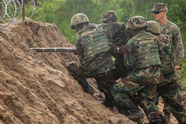 U.S. Marine Sgt. Sam Adkins and Uganda People’s Defense Force soldiers emplace explosives through the dirt during a breaching exercise at Camp Singo, Uganda, Dec. 1, 2015. (Photo: Cpl. Olivia McDonald)