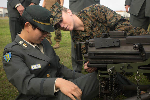 Cpl. Malynn Ochsner shows Japan Ground Self-Defense Force Officer Candidate Ayako Yukawa how to operate a MK19 machine gun, MOD 3 on Camp Kinser, Okinawa, Japan, Jan. 15. (Photo: Cpl. Robert D. Williams Jr.)