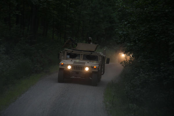 Humvee with headlights on at night.