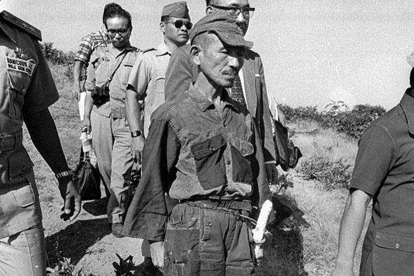 In this 1974 file photo, Hiroo Onoda, wearing his 30-year-old imperial army uniform, cap and sword, heads for a helicopter landing site on Lubang Island for a flight to Manila when he comes out of hiding in the jungle.