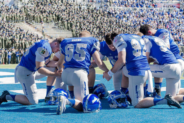 Members of the Air Force Academy's football team pray together before a game; their public religious displays are now being investigated by the academy. (DoD photo)