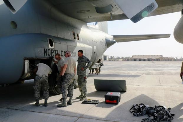 Crew members from the 386th Expeditionary Aircraft Maintenance Squadron inspect a C-130 on a flightline in Iraq after its engines overran in the heat. (Military.com photo by Oriana Pawlyk)