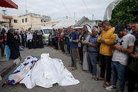 Mourners pray over the bodies of Palestinians who were killed in an Israeli airstrike in Gaza Strip