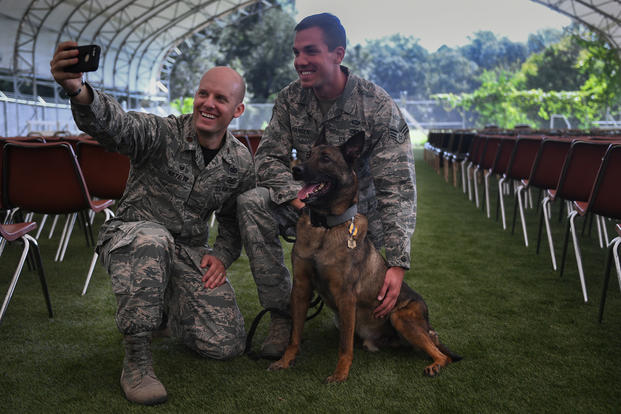 Maj. Ryan Natalini, 2nd Security Forces Squadron commander, Senior Airmen Travis Hansen, 2nd Security Forces military working dog handler, and Marco all pose for a selfie at Barksdale Air Force Base, La., Sept. 8, 2017. Marco served as a military working dog in the U.S. Air Force for more than six years. (U.S. Air Force/Stuart Bright)