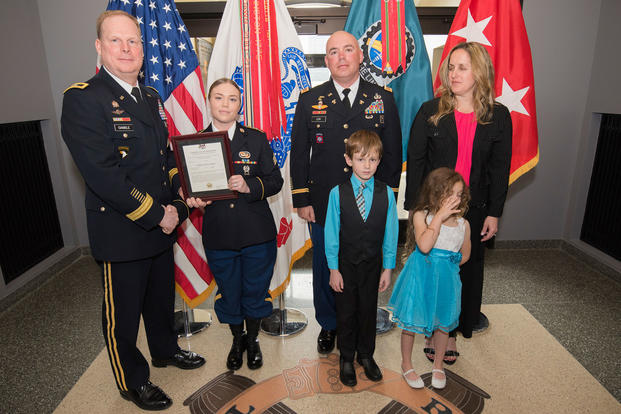 Maj. Gen. Duane Gamble, commanding general, U.S. Army Sustainment Command, presents a promotion certificate to Sgt. Kaitlin Reyes during a promotion ceremony March 30, 2018 in the foyer of the ASC Headquarters, Building 390, Rock Island Arsenal, Illinois. Reyes was promoted the same day as her father as she transitions to a new position at the Headquarters and Headquarters Company, Group Support Battalion, 5th Special Forces Group, Fort Campbell, Kentucky. (U.S. Army photo/Kevin Fleming)