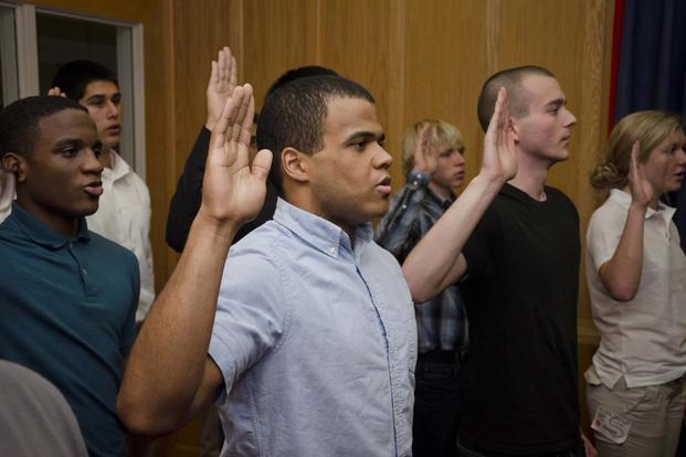 Jorge Estevez, center, recites the oath of enlistment in the Cpl. Jennifer M. Parcell Ceremony Room at the Military Entrance Processing Station aboard Fort George G. Meade, Md., Dec. 2, 2013. (U.S. Marine Corps/Cpl. Bryan Nygaard)