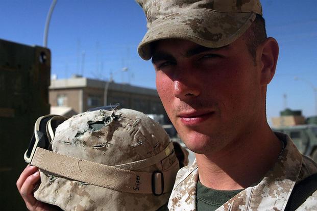 Lance Cpl. Bradley A. Snipes stands with the helmet that saved his life. During a mission with his platoon, Snipes was shot in the head by an enemy sniper. The only thing that saved his life was the Kevlar helmet he wore. (U.S. Marine Corps/Sgt. Jerad W. Alexander)