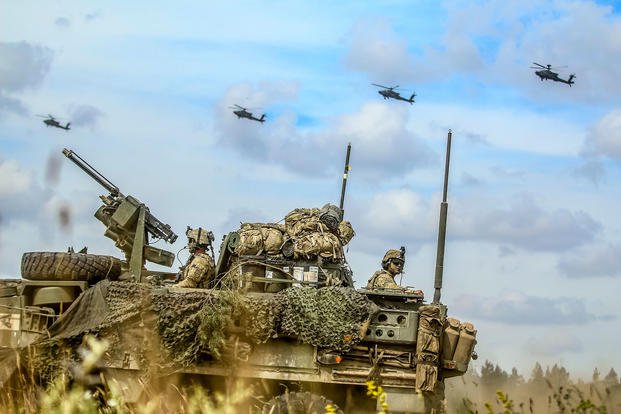 U.S. soldiers in an interim armored vehicle and AH-64 Apache helicopters with Battle Group Poland move to secure an area during a lethality demonstration for exercise Puma 2 at Bemowo Piskie Training Area, Poland, June 15, 2018, as part of Saber Strike 18. (U.S.Army photo by Spc. Hubert D. Delany III)