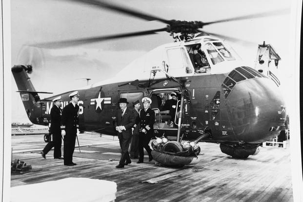 This photograph is of President Dwight D. Eisenhower disembarking from a U.S. Marine Corps helicopter that landed on board the USS Des Moines in the harbor of Athens, Greece. Behind President Eisenhower is his Naval Aide, CAPT Evan P. Aurand. Eisenhower was visiting Greece from December 14–15, 1959 as part of an 11-nation goodwill tour. (White House Historical Association)