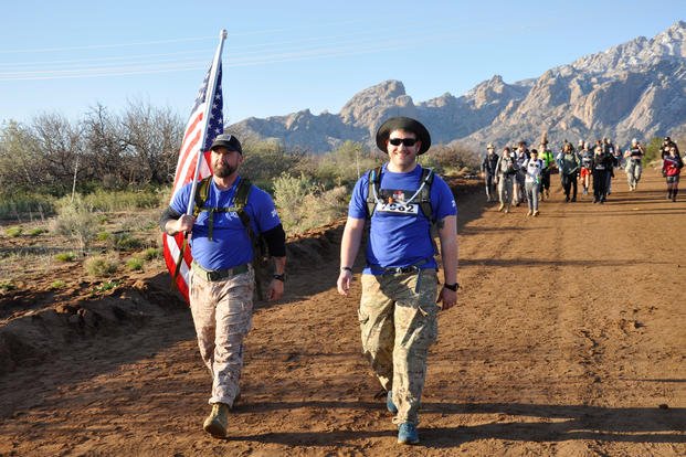 Bret Baker (left) of Albuquerque NM, and Alexander Stelly (right) from Miami FL tackle the march flag in hand. The two are marching in support of the Wounded Warrior Project, March 17, 2019. (U.S. Army photo/Caleb Creech)