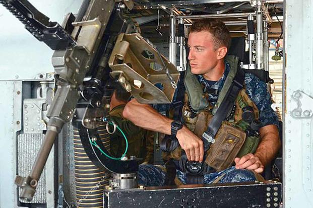 Fleet replacement Aircrewman (FRAC) Eugene Schoen, with Helicopter Sea Combat Squadron (HSC) 2, demonstrates the typical seated position of an MH-60 gunner in May. Note that the barrel on the M240 gun is missing. (U.S. Navy photo by Mikel Lauren Proulx)