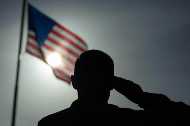 An airman salutes the U.S. flag.