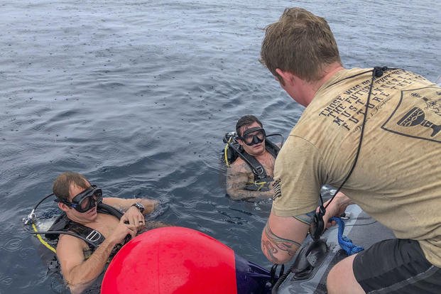 Three explosive ordnance disposal technicians prepare to locate simulated underwater training mines as part of Exercise HYDRACRAB, Aug. 26, 2019.  (U.S. Navy/Mass Communication Specialist 1st Class Billy Ho)