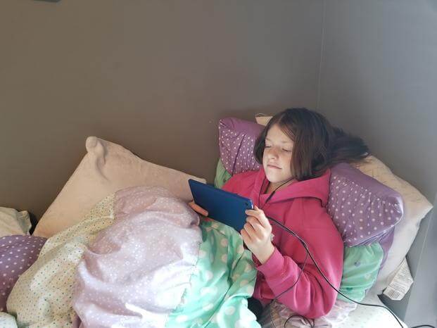 girl sitting on bed looking at kindle
