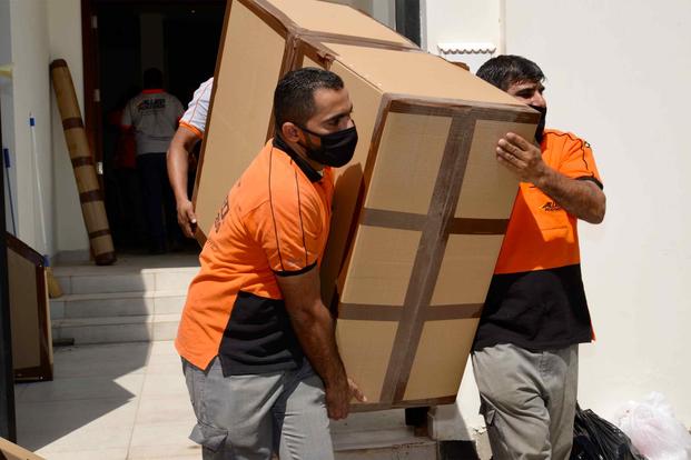 Movers carry a heavy box to the truck during the a household goods move amid the COVID-19 crisis.