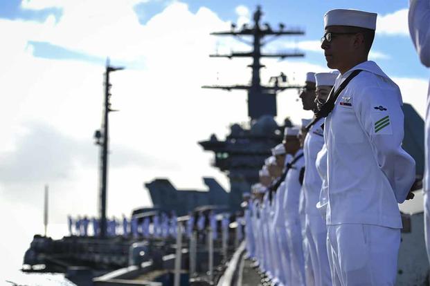 U.S. Sailors man the rails aboard the aircraft carrier USS Nimitz.