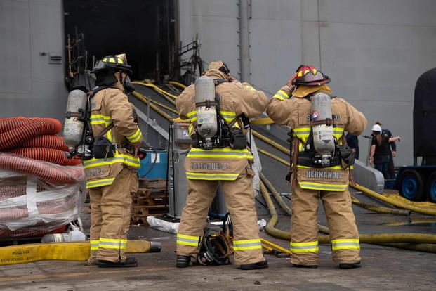 Sailors and Federal San Diego Firefighters prepare to fight a fire on board USS Bonhomme Richard.