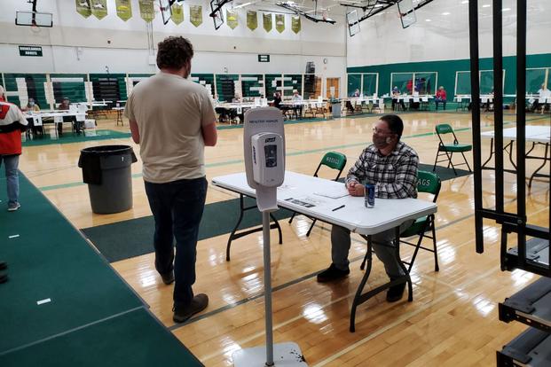 A Wisconsin National Guard member checks voters into a polling place. 