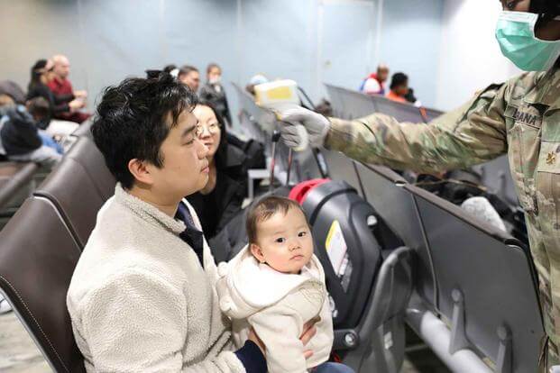 An Army medical professional takes the temperature of a recent arrival at Osan Air Base.