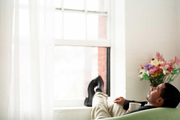 Man sitting in small apartment with feet on windowsill