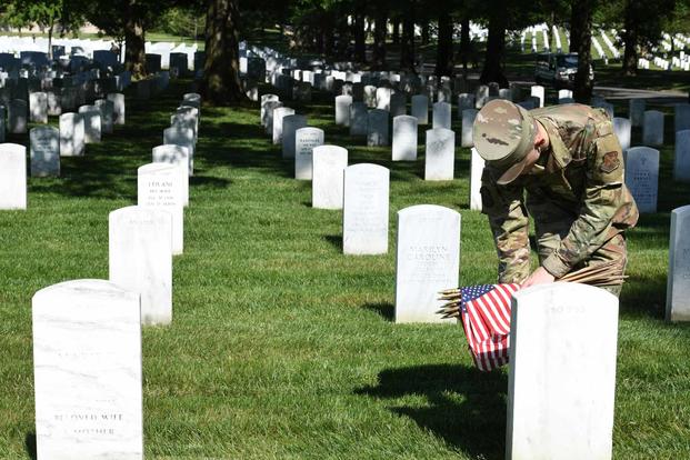 Airman places an American flag in Arlington National Cemetery.