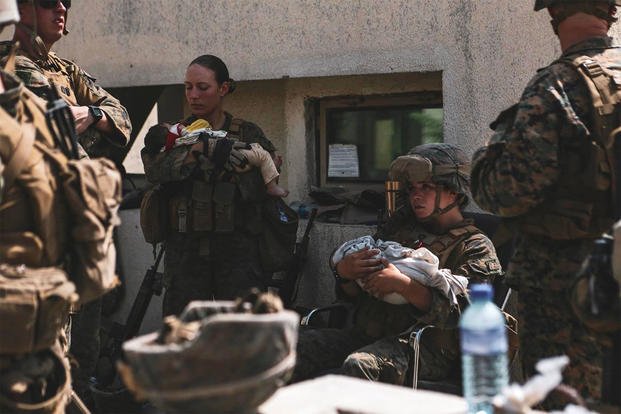 U.S. military service members comfort infants at Hamid Karzai International Airport in Kabul, Afghanistan. 