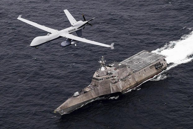 an MQ-9 Sea Guardian drone flies over the USS Coronado 