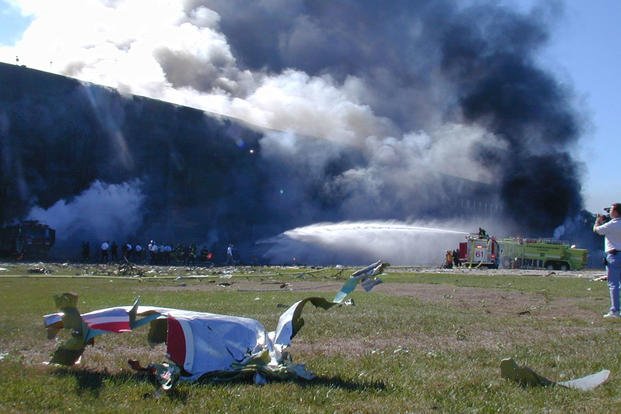 A piece of aircraft lies in the grass while fire crews work to put out the flames in the minutes after the attack, 11 September 2001. 