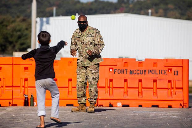 A soldier plays catch with an Afghan refugee at Fort McCoy.