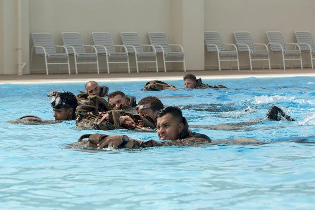 Marines and sailors use fins to race during a training exercise.