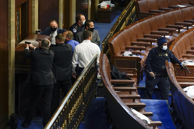 U.S. Capitol Police with guns drawn stand near a barricaded door