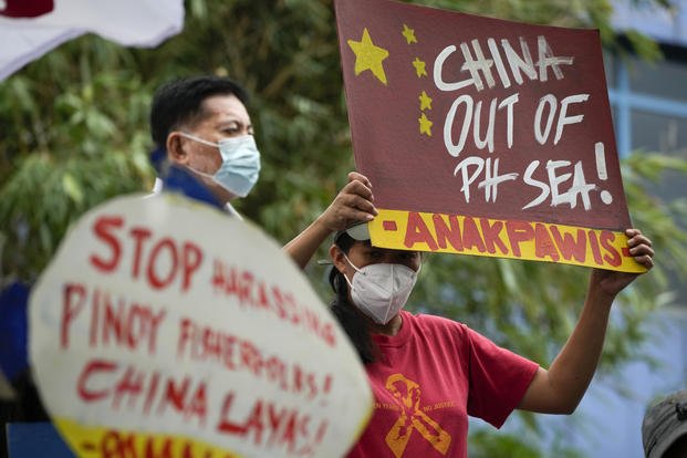 Activists hold slogans as they protest outside the Chinese consulate in Makati, Philippines. 