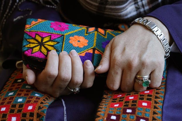 A Massachusetts resident identAn Afghan woman living in Massachusetts holds a purse with traditional Afghan patterns.