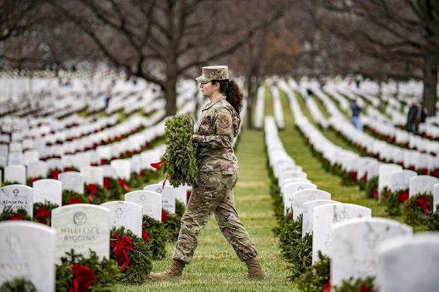 A service member participates in National Wreaths Across America Day at Arlington National Cemetery, Va., Dec. 18, 2021. During the annual event, nearly 38,000 volunteers place 257,000 wreaths at every gravesite, columbarium court column and niche wall column at Arlington National Cemetery.