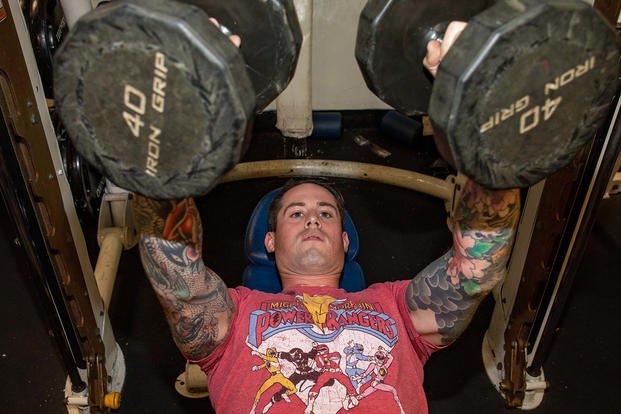 A sailor performs the bench press with dumbbells.