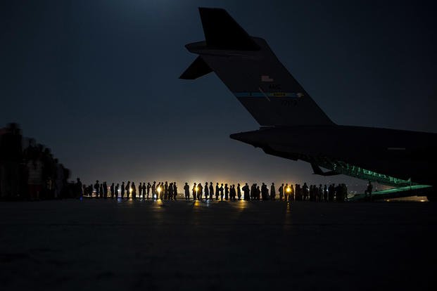 Airmen prepare to load qualified evacuees aboard a C-17 Globemaster III aircraft at Hamid Karzai International Airport in Kabul, Afghanistan.