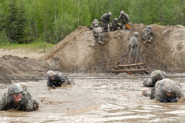 Soldiers endure a cold muddy water obstacle in Alaska as part of the annual spur ride.