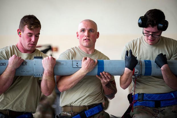 Three airmen compete in a weapons loading contest.